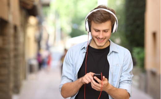 Young man wearing white headphones listening to music on his phone